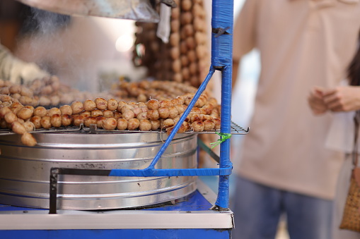 Two young tourists are walking on the street in a market in Thailand. Young couple shopping and eating on street food. Happy tourist Asian enjoy and fun traditional asian street food at Thailand.