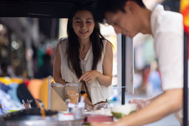 street food thailand. merchant scooping ice cream. asian tourist friends walking on the street market, they are buying delicious ice cream. - women eating ice cream indigenous culture ストックフォトと画像