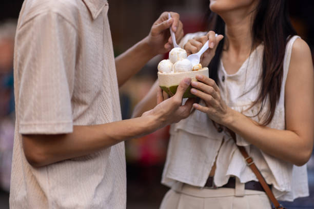 asian tourist friends are walking on the street in the retail market, they are buying delicious ice cream on street food. - women eating ice cream indigenous culture ストックフォトと画像