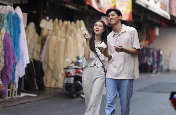 asian tourist friends are walking on the street in the retail market, they are buying delicious ice cream on street food. - women eating ice cream indigenous culture ストックフォトと画像