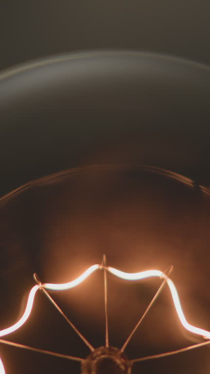 Extreme close-up wires inside light bulb lighting up with bright light