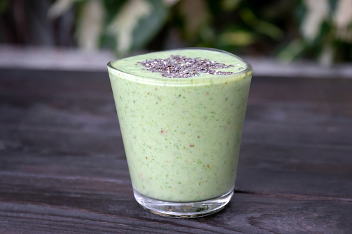 Healthy green kale smoothie greek yogurt with chia seeds in glass on wooden table background, top view. Superfood of drink a great source of vitamins and minerals.