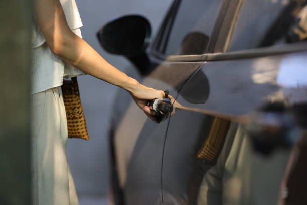 Woman hand on grey car door handle.