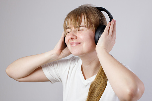 woman 30s listens to music on headphones on a gray background