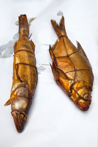 Appetizing smoked freshwater zander and common bream fish in smokehouse. Beautiful delicious dried smoked fish with spices for home use on white paper.