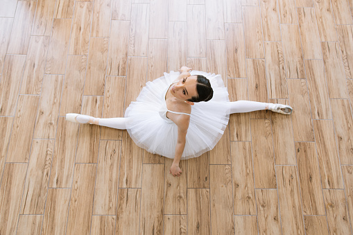 A little girl ballerina is dancing on stage in a white tutu on pointe shoes a classic variation.
