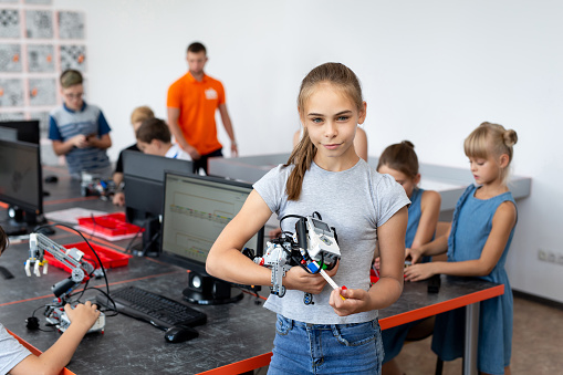 Portrait Of Female Student Building Robot Vehicle In After School Computer Coding Class