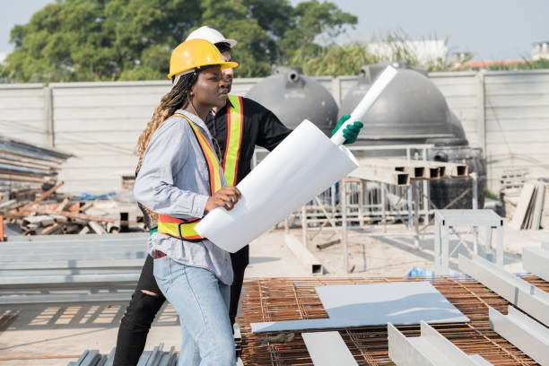 Male and female foreman builder working together at construction site. Male engineer construction working at construction site. Female engineer working at construction site