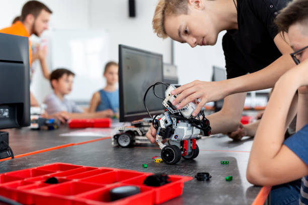 istock Smart schoolboy sitting at the table and constructing a robotic device in a school lesson. 2060795891