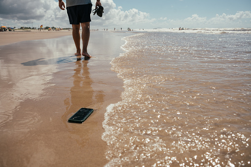 Man walking along the beach and forgetting his cell phone in the sand