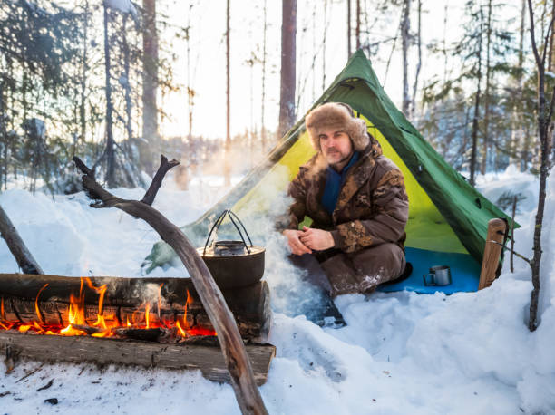 istock Man Enjoying a Warm Campfire Outside His Tent in a Snowy Forest at Dusk 2060804976