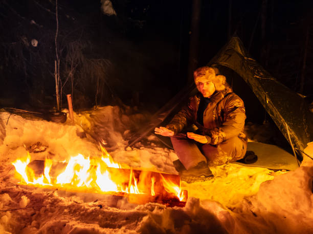 istock Man Sitting Next to Long Fire in Snow 2060804983