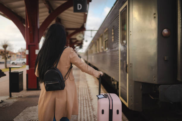 Back of a businesswoman on the railroad station with a suitcase.