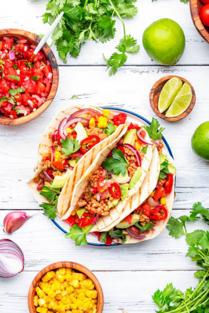 istock Tacos with ground beef, sweet corn, red beans, tomato salsa sauce and red onion in corn tortillas on plate. Mexican cuisine. Taco party menu. White table background, top view 2060812973