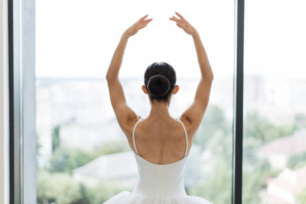 Portrait of an elegant ballet dancer standing on doorway at abandoned place and smiling at the camera. Graceful ballerina gently enters the abandoned room in ruined house. Copy space.