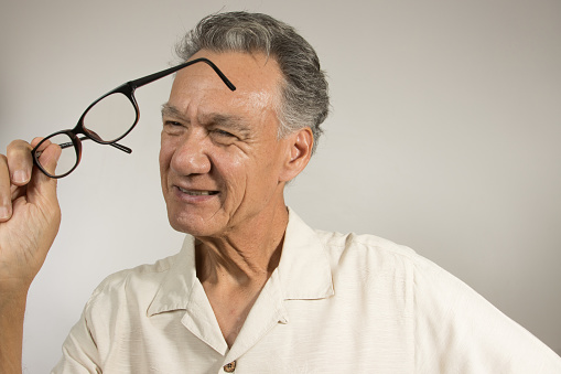 Man cleaning and checking out his glasses with a microfiber cloth
