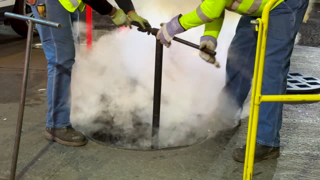 Workers working on a steaming manhole in New York City, USA