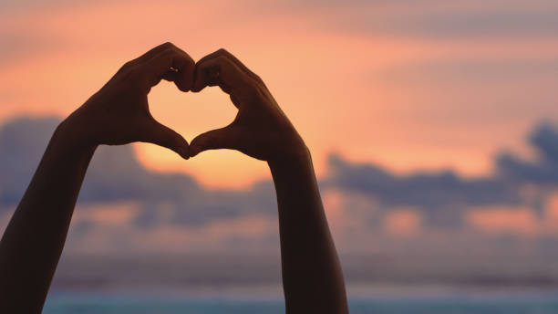 istock Hands forming a heart shape with sunset silhouette 2060830577
