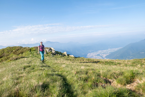 Join a young woman on a summer hike, ascending a mountain trail with each step. Against the backdrop of sunlit peaks, her journey embodies the simplicity and beauty of summertime exploration