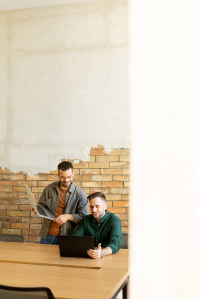 istock Collaboration in Motion, Professionals Working Together in a Modern Brick-Walled Office 2060840364