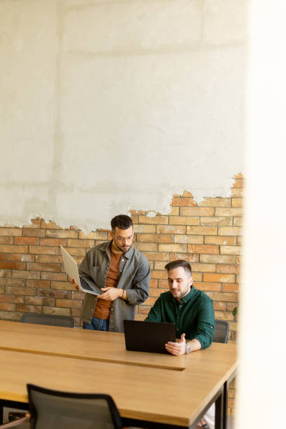 istock Collaboration in Motion, Professionals Working Together in a Modern Brick-Walled Office 2060840900