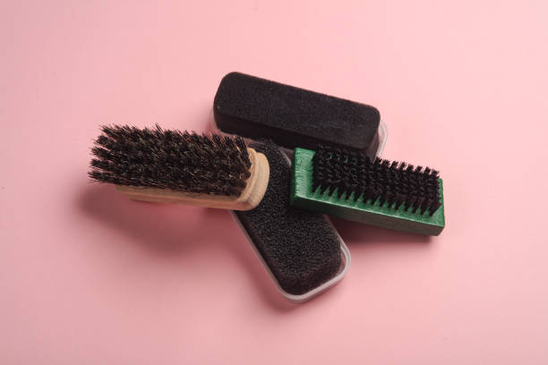Shoe brushes and sponges on pink background