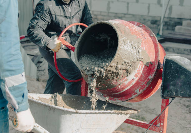 Worker pouring concrete with cement mixer at construction site, closeup.