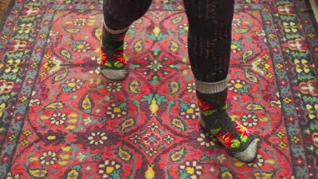 legs in colorful ornate warm wool socks on old ornate red carpet