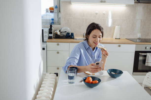 istock Young beautiful woman having breakfast at home and using smart phone 2060876443