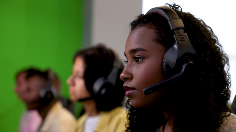 Focused female worker at a call center wearing a headset looking at the computer screen