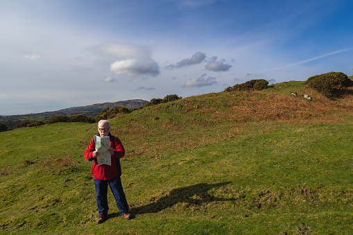 Retired man checking his map in a remote rural location in Scotland on a spring morning