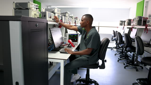 African American maintenance engineer fixing medical equipment using his computer
