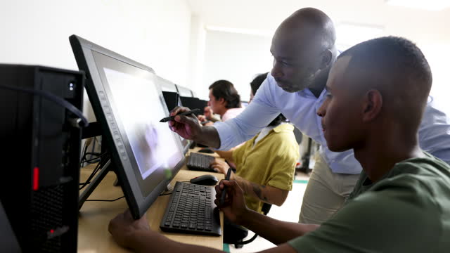 Cheerful teacher helping a black male student edit an image during class