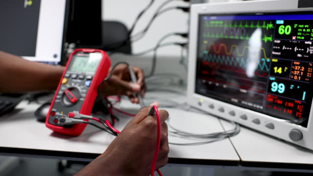 African American electrician repairing medical equipment using a multimeter