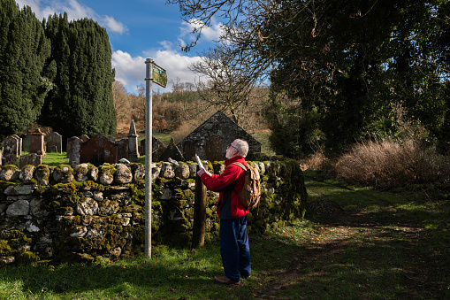 Senior man looking at a footpath sign in a rural location in Scotland on a spring morning
