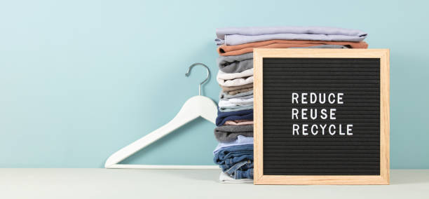 Black letter box and stack of folded clothes on blue background, reduce,reuse,recycle quote 스톡 사진