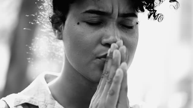 One faithful young black woman PRAYS to GOD, close-up face of a person of African descent having HOPE and FAITH during challenging times