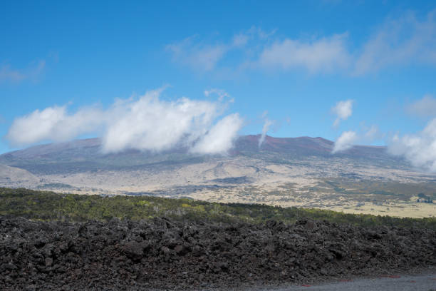 A serene Hawaiian landscape featuring volcanic terrain under a vividly blue sky. The rolling hills display golden hues, embodying the spirit of a tropical paradise. Perfect as a vacation or tourism destination. A beautiful volcanic landscape with rolling hills set against a blue sky in Hawaii. BIG ISLAND. Hawaii.