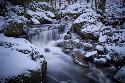 Flowing waterfall (Selkefall) in a snow-covered winter forest