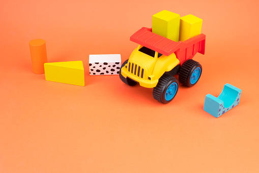 Top view of colorful wooden bricks on the table. Early learning. Educational toys on a orange background. For the development of the child.