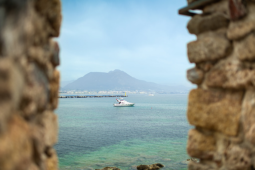 View to the sea and sailing ship through old walls of Alanya fortress, Turkey