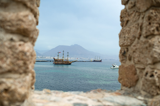 View to the sea and sailing ship through old walls of Alanya fortress, Turkey