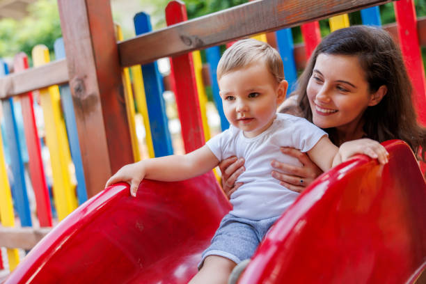istock Mother helping her son while playing on a slide in the park 2061010319