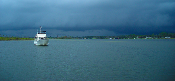 Dark stormy clouds, approaching anchored boat in Bay
