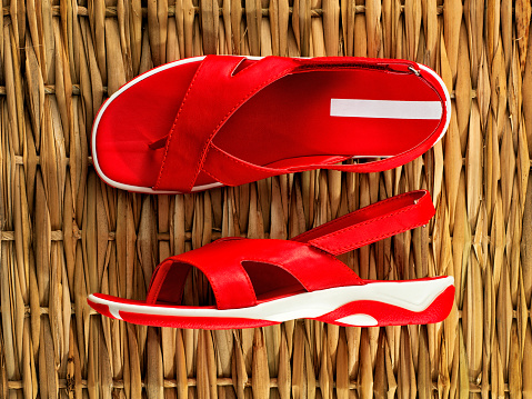 High angle view of woman wearing beach sandals feet standing on white sand beach.