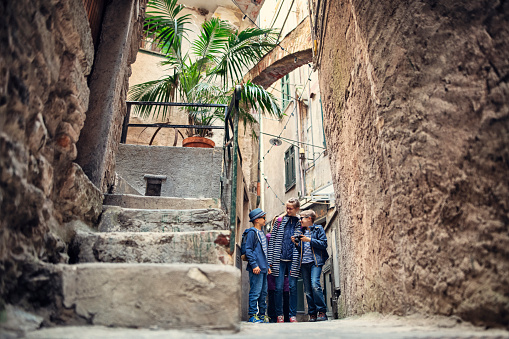 Family sightseeing beautiful Italian town of Vernazza.  One of the five towns in Cinque Terre National Park - a UNESCO World Heritage Site. Three kids are walking beautiful, narrow streets of the old town.
Shot with Nikon D850