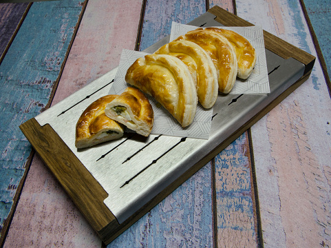 Closeup view of traditional chicken empanadas made with phyllo dough in a metal board.