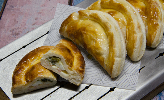 Closeup view of traditional chicken empanadas made with phyllo dough in a metal board.