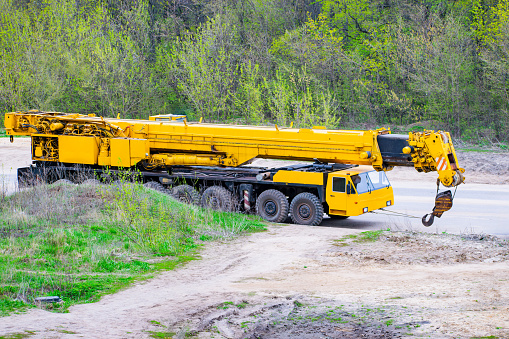 yellow automobile mobile crane parked next to a construction site against a background of trees. close-up