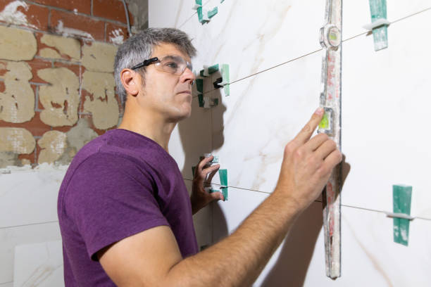 Tiler with protective glasses checking the installation with a hand level a tile wall in a bathroom renovation